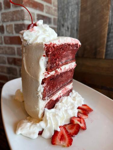a piece of red velvet cake on a plate with strawberries at Quality Inn & Suites Galveston - Beachfront in Galveston