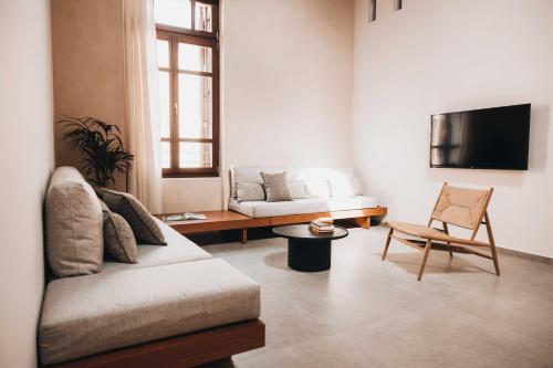 uma sala de estar com um sofá e uma televisão em MAZI - Pied à Terre em Rethymno Town