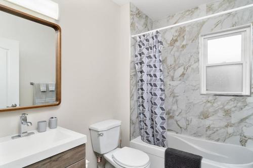 a bathroom with a toilet and a tub and a sink at Fields Inn Executive Townhouse in Kingston