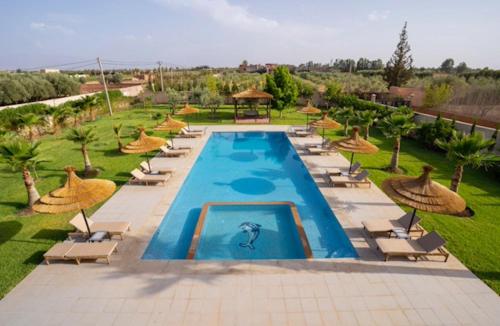 an outdoor swimming pool with chairs and umbrellas at Villa Leila Farmhouse in Marrakech