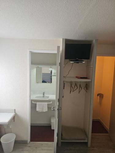 a bathroom with a sink and a tv on the wall at Hôtel Restaurant du Lac in Graulhet