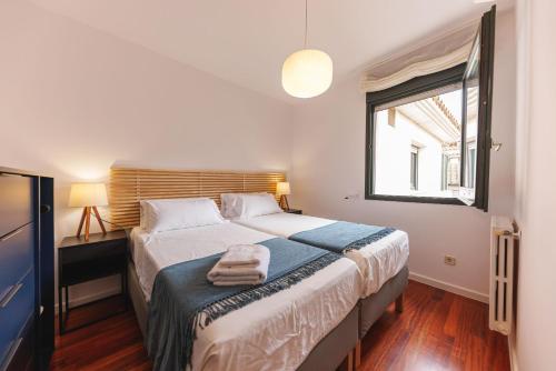 a bedroom with a bed with two towels on it at Bravissimo Cort Reial Palau, Duplex penthouse in Girona