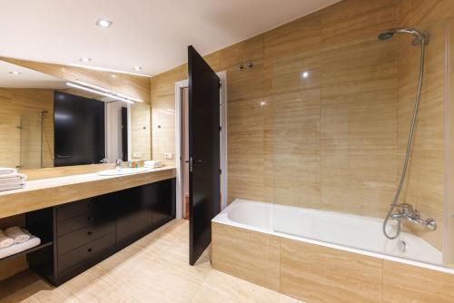 a bathroom with a tub and a sink at Bravissimo Cort Reial Palau, Duplex penthouse in Girona