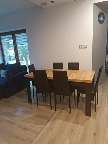 a dining room with a wooden table and chairs at Apartament nad potokiem in Domaszków