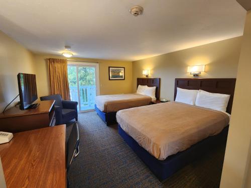 a hotel room with two beds and a television at Hyannis Travel Inn in Hyannis