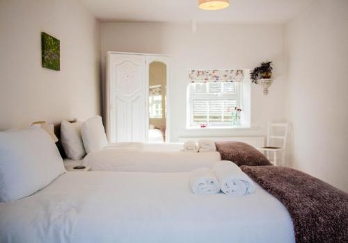 a white bedroom with two beds with towels on them at Dalesmoor in Reeth