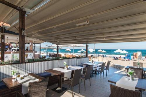 restauracja ze stołami i krzesłami oraz plaża w obiekcie Апартамент Б306 в Обзор Бийч Резорт на първа линия с перфектен изглед към плажа! w Obzorze