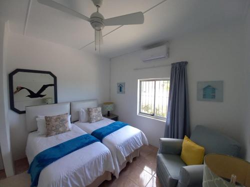 a bedroom with two beds and a couch and a window at Ocean rush Seagull in Zinkwazi Beach