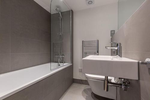 La salle de bains est pourvue d'un lavabo, d'une baignoire et de toilettes. dans l'établissement Kensington Olympia Apartment, Breakfast, à Londres