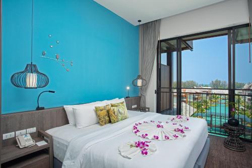 1 dormitorio con 1 cama grande y pared azul en 普吉岛-迈考海滩水疗度假村PL- Maikhaolak Beach Village en Khao Lak