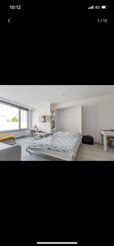 a white bedroom with a bed and a table at Charmante studio op toplocatie aan Meir. in Antwerp