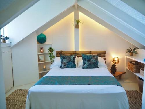 a bedroom with a large white bed with blue pillows at Little Diamond, Wooden Jungle House. Bathsheba. in Saint Joseph
