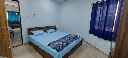 Un dormitorio con una cama con sábanas azules y una ventana. en SHIV SHAKTI HOMESTAY, en Kevadia