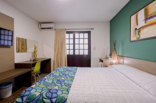 a bedroom with a bed and a desk and a window at Pousada Casamar in Porto De Galinhas