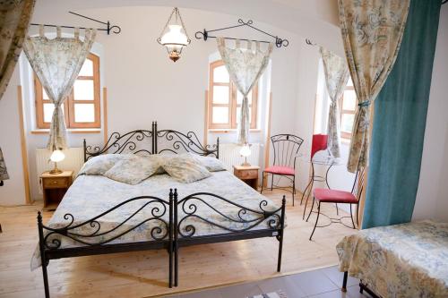 een slaapkamer met een bed en 2 stoelen en ramen bij Somogy Kertje Üdülőfalu és Étterem in Bonnya