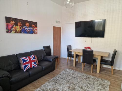 a living room with a black couch and a table at Liverpool city 5 bed house sleeps 12 in Liverpool