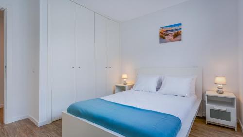 a white bedroom with a bed and two lamps at Brand New 2 BDR Flat W/Rooftop Pool by LovelyStay in Olhão