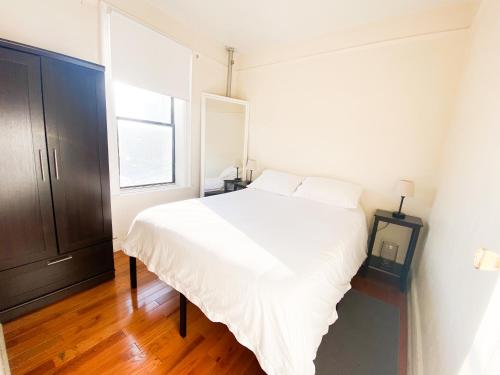 um quarto com uma cama branca e uma janela em 2 Bedrooms Entire Beautiful Apt in Williamsburg! em Brooklyn