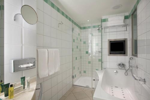 a bathroom with a shower and a tub and a sink at Hilton Zurich Airport in Opfikon