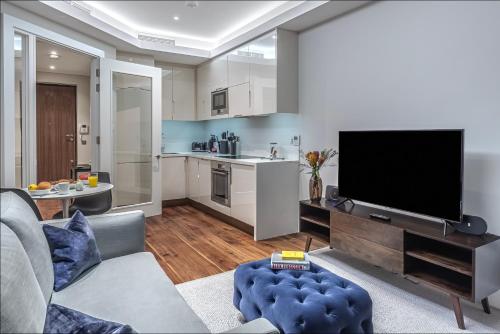 a living room with a flat screen tv and a kitchen at Grays Inn by Q Apartments in London