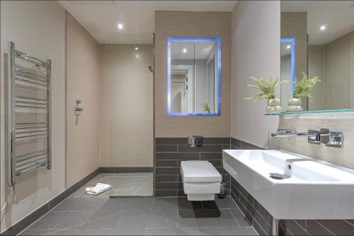 a bathroom with a sink and a toilet and a mirror at Grays Inn by Q Apartments in London