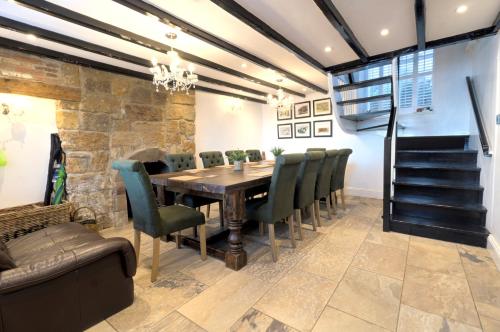 une salle à manger avec une table en bois et des chaises vertes dans l'établissement Harbourside, à Staithes