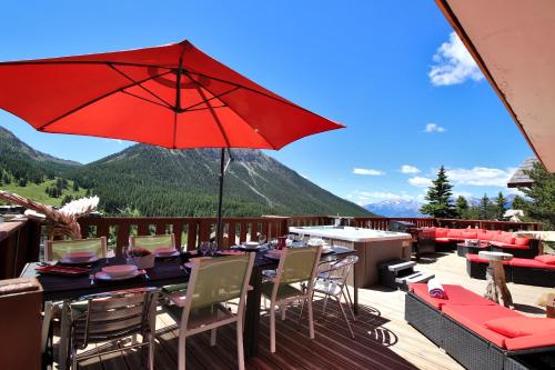 a patio with a table and a red umbrella at Spacious Chalet 16/18 Guests w/Slope View, Jacuzzi et Sauna in Montgenèvre