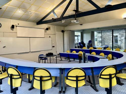 an empty classroom with blue tables and yellow chairs at Logis Hôtel Le Keréden in Locarn