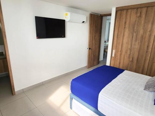 een slaapkamer met een bed en een flatscreen-tv bij Apartamento para estrenar Ambar Roca - Bedviajes in Santa Marta