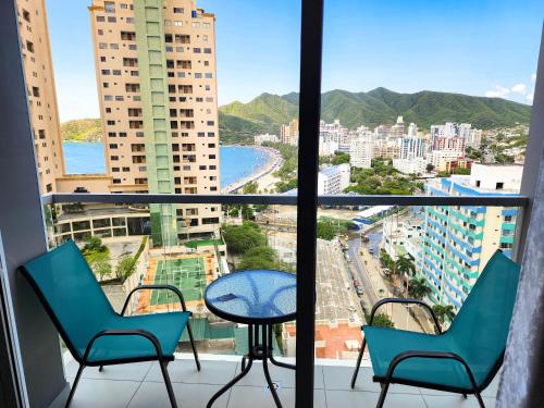 een balkon met stoelen en een tafel en uitzicht op de stad bij Apartamento para estrenar Ambar Roca - Bedviajes in Santa Marta