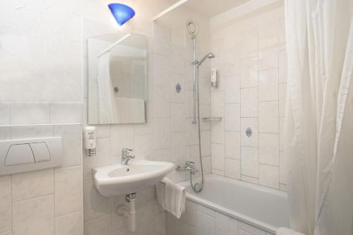 a white bathroom with a sink and a shower at Apart-Hotel Zurich Airport in Opfikon