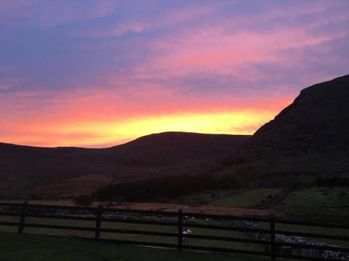 a sunset with a fence and mountains in the background at Cois Locha in Glenbeigh