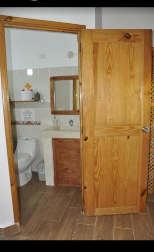 a bathroom with a toilet and a wooden door at Hotel Piedra Marron in Las Terrenas