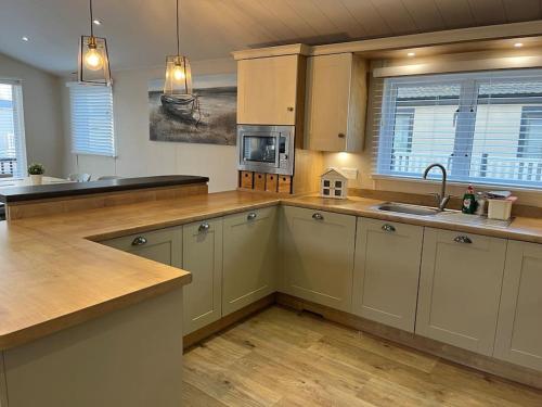 a kitchen with white cabinets and a wooden floor at Lakeview Lodge in Chichester