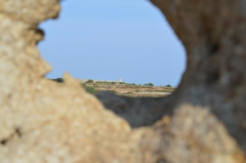 a view of a field through a hole in a rock at Agriturismo Casa del Peperoncino in Otranto