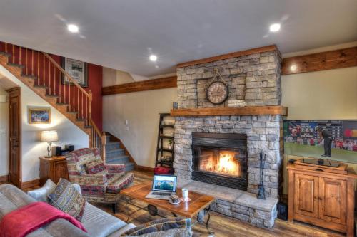 a living room with a fireplace and a staircase at Plateau A - Mont-Tremblant in Mont-Tremblant