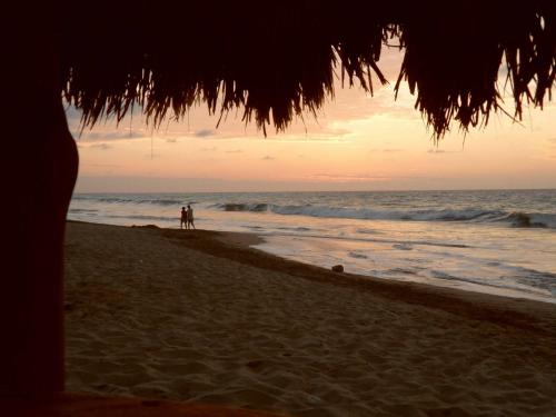 two people standing on a beach with the ocean at Los Sonidos de las Olas in Santa Marianita