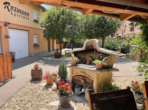 a patio with a stone fireplace in a garden at Rozmann Family Panzió & Apartmanhaz in Sárvár