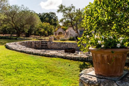 a garden with a stone wall and a potted plant at Sopra i Sassi - Villa & Trulli in Ostuni