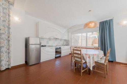 a kitchen with a table with chairs and a refrigerator at Azzurro Mare a Seccheto - Goelba in Seccheto
