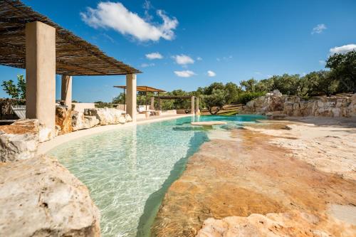 a swimming pool in a resort with a beach at Sopra i Sassi - Villa & Trulli in Ostuni