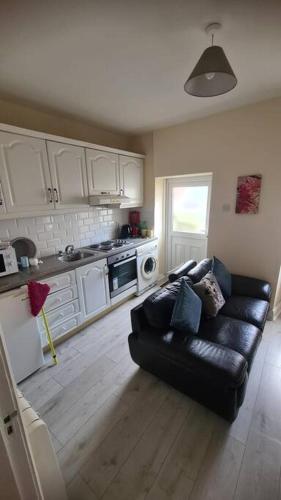 a living room with a black couch in a kitchen at Apartment 1, Regent Street in Bagenalstown