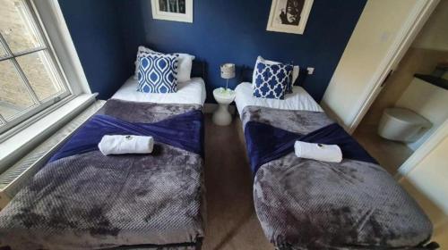 two beds in a room with blue walls at The Hepburn Suite - In Central Bath in Bath