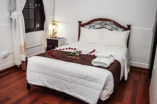 Un dormitorio con una gran cama blanca con flores rojas. en Casona Valdelirios Hotel, en Ayacucho