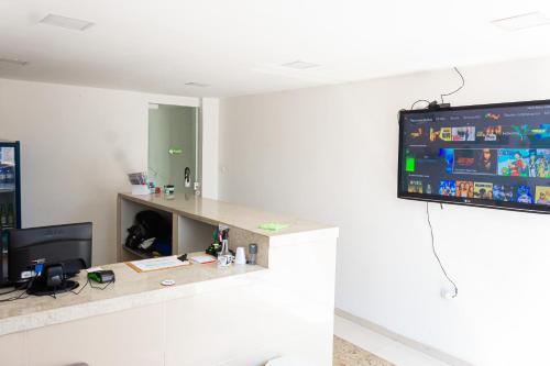 an office with a tv on a wall with a desk at Hotel Grandville III in Palmeira dos Índios