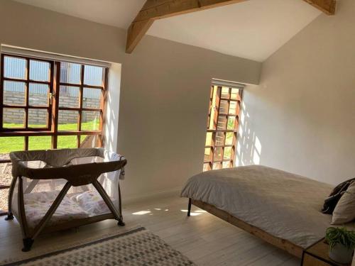 ein Schlafzimmer mit einem Bett und einem großen Fenster in der Unterkunft Light & Airy Vaulted Barn Conversion with a View in Sampford Arundel