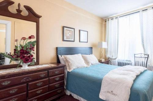 a bedroom with a blue bed and a dresser and a mirror at Stunning 3BR Apartment in NYC! in New York