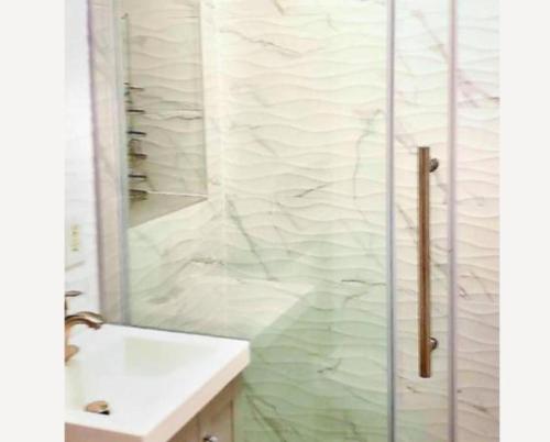 a bathroom with a shower and a white sink at Stunning 3BR Apartment in NYC! in New York