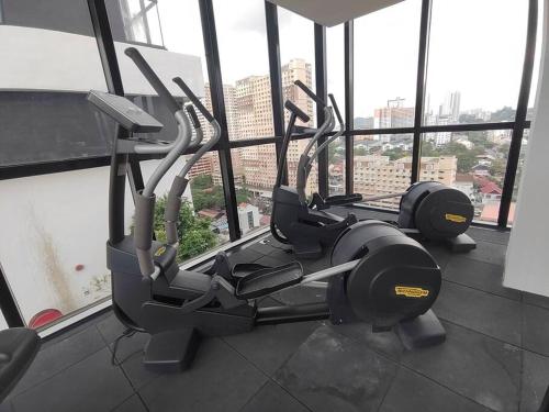a gym with three cardio machines in a room with windows at Seaview Infinity Pool #6pax #2bedroom #2bathroom in Jelutong