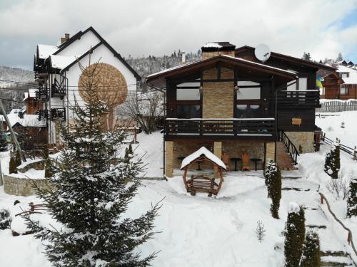 a house in the snow with a christmas tree at Stara Pravda Hotel - Vykrutasy in Bukovel